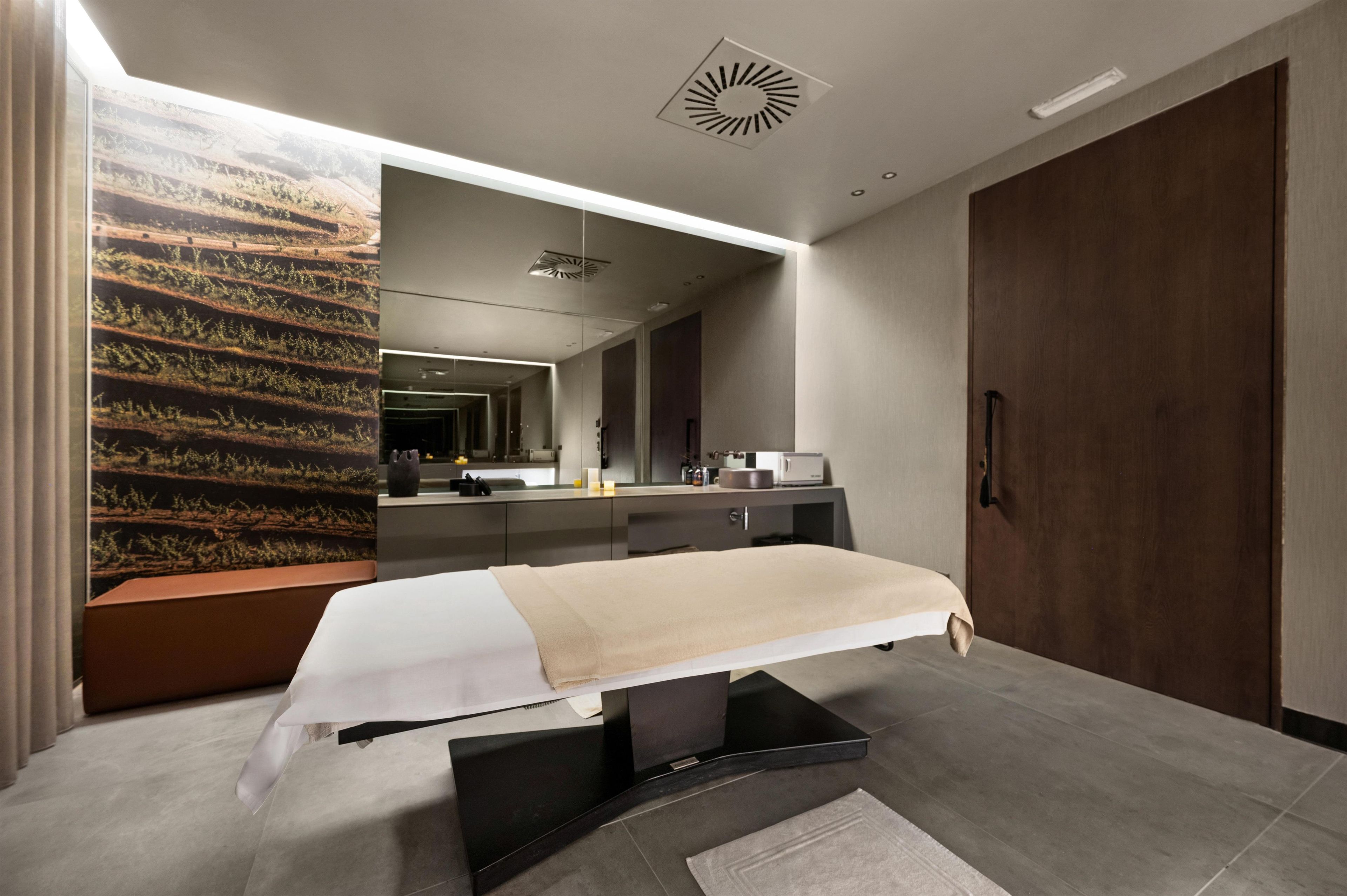 A modern bedroom with a bed, a large mirror, a wardrobe, and a wall-mounted artwork.