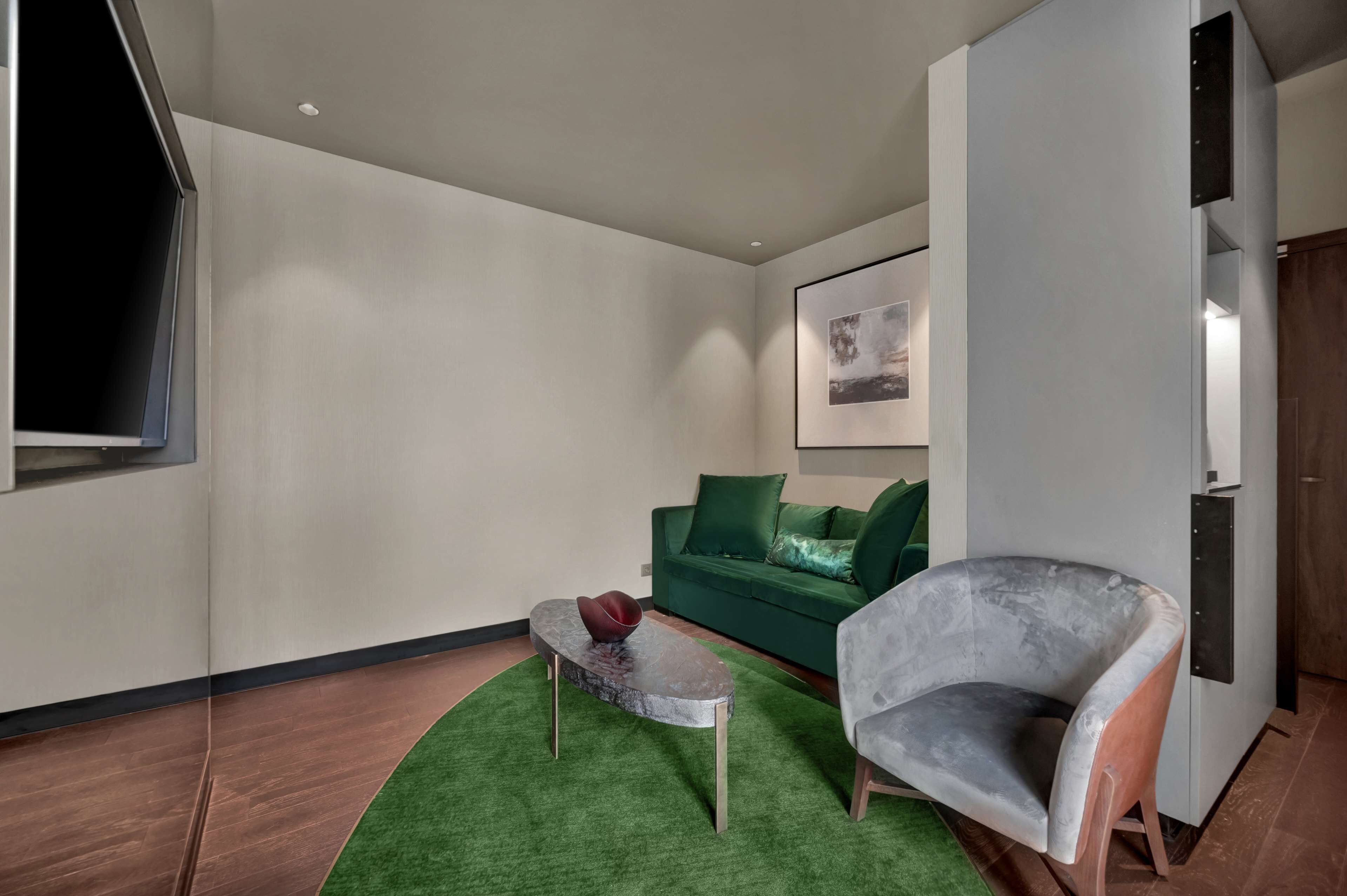 Un salon moderne avec un canapé vert, un fauteuil gris et une petite table basse.