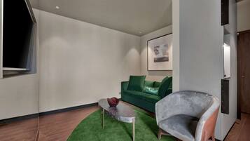 Un salon moderne avec un canapé vert, un fauteuil gris et une petite table basse.