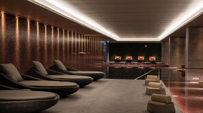 A spa area with a brick wall, massage chairs, and a pool. - Hilton Porto Gaia (Vila Nova de Gaia)