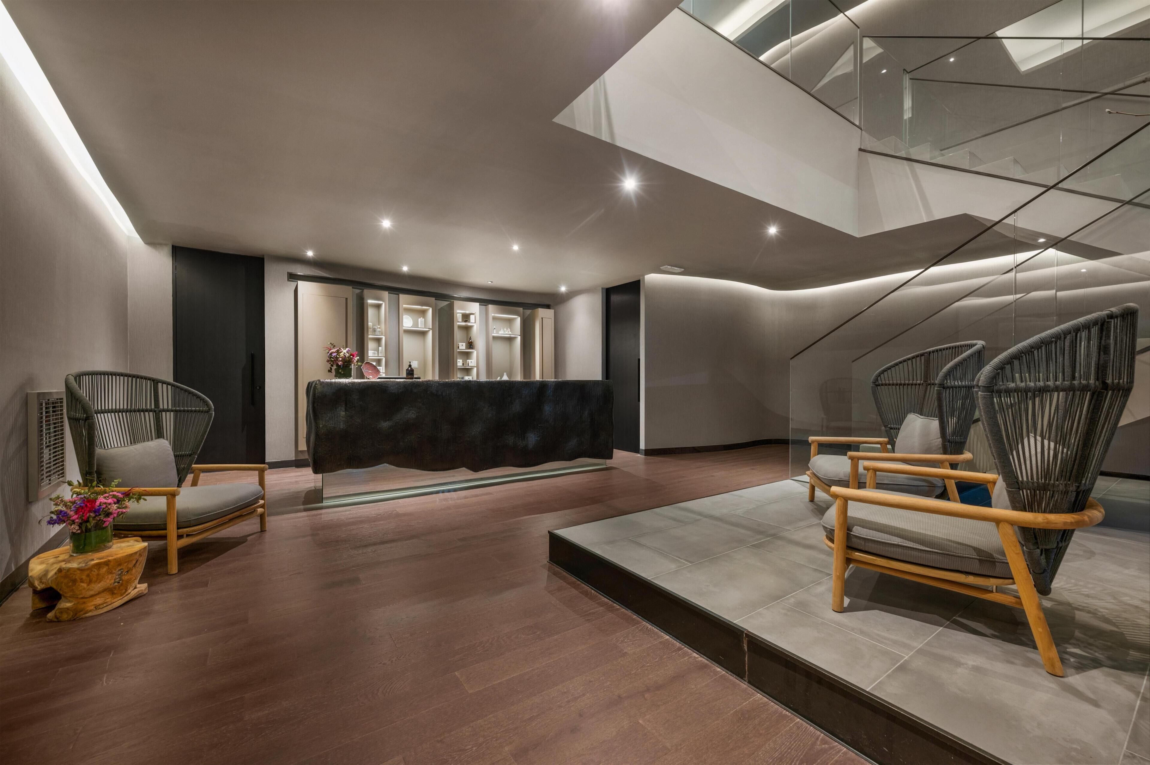 Un vestíbulo moderno con mostrador de recepción, sillas de mimbre y suelo de madera.