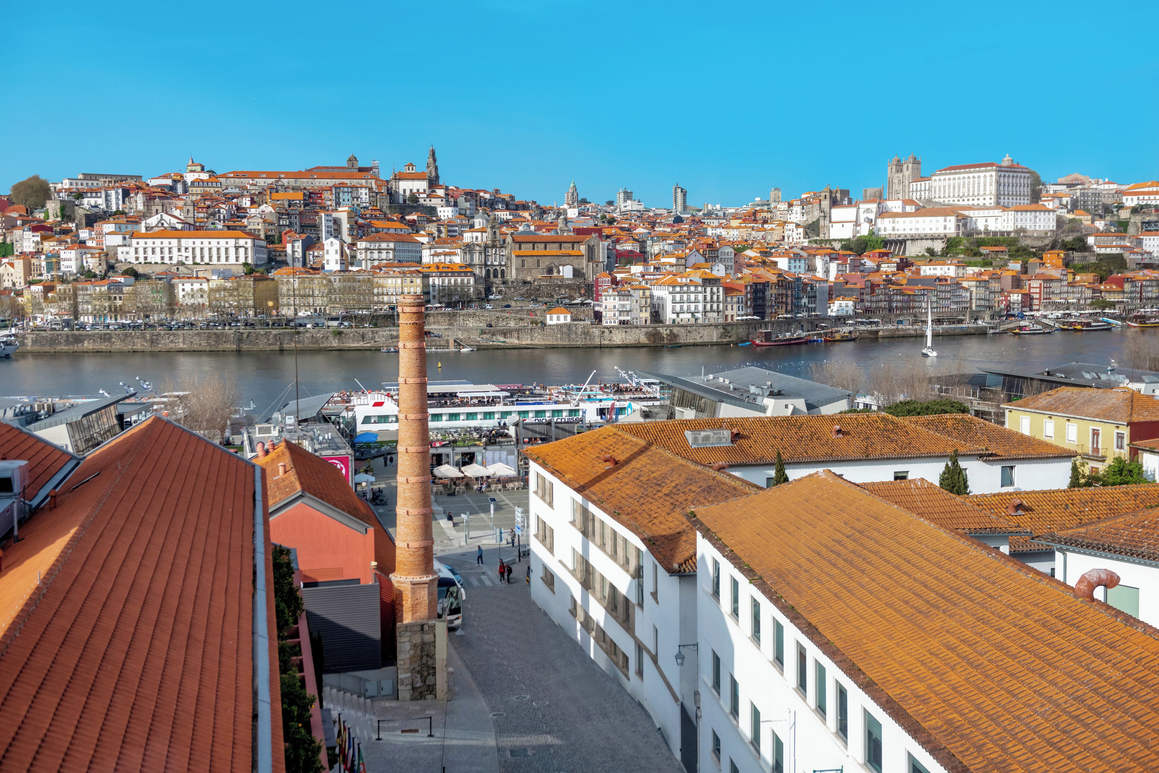 A historic cityscape with a prominent tower, a river, and a mix of traditional and modern architecture.