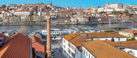 Un paisaje urbano histórico con una torre destacada, un río y una mezcla de arquitectura tradicional y moderna.