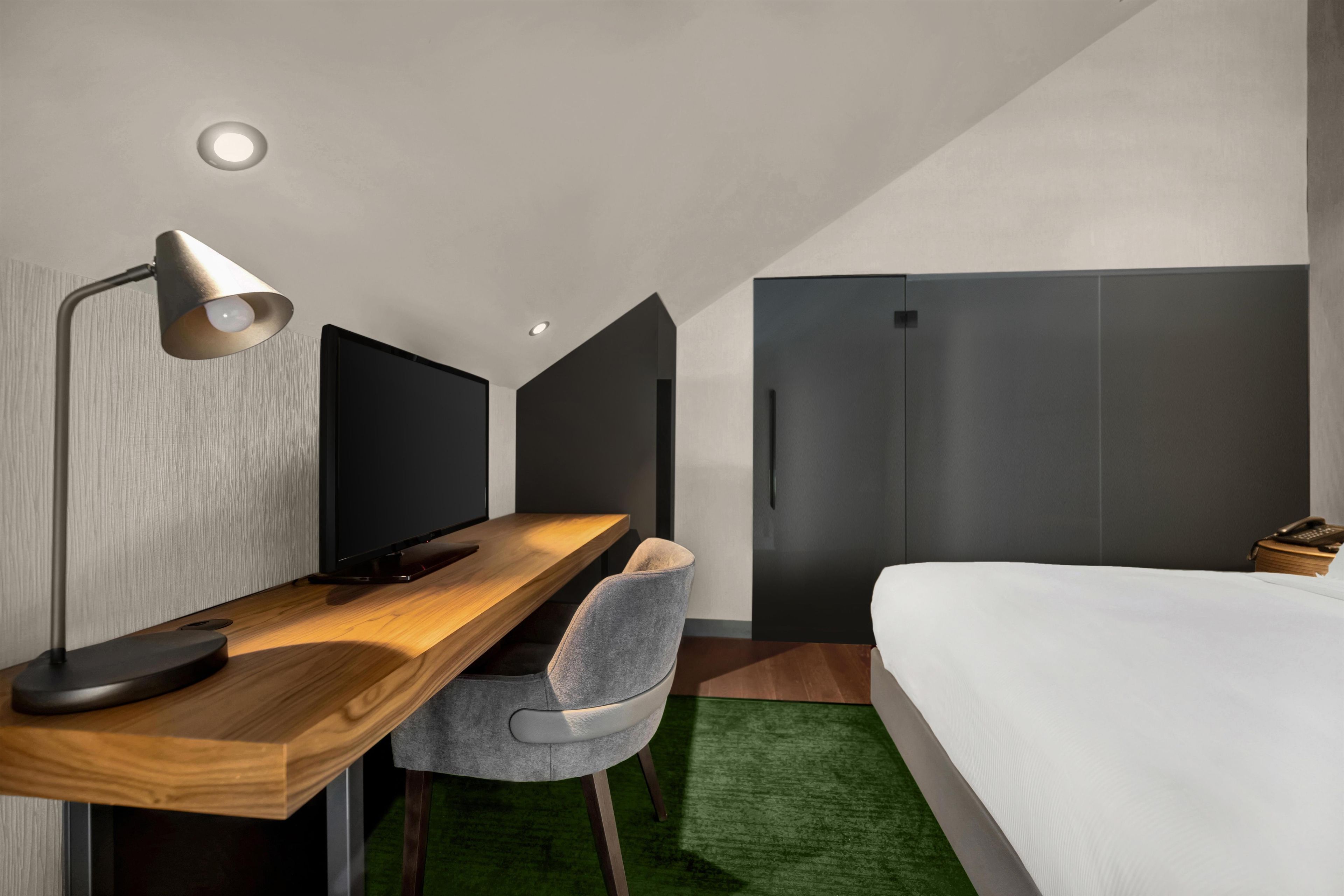A modern bedroom with a wooden desk, a chair, a bed, and a wardrobe.