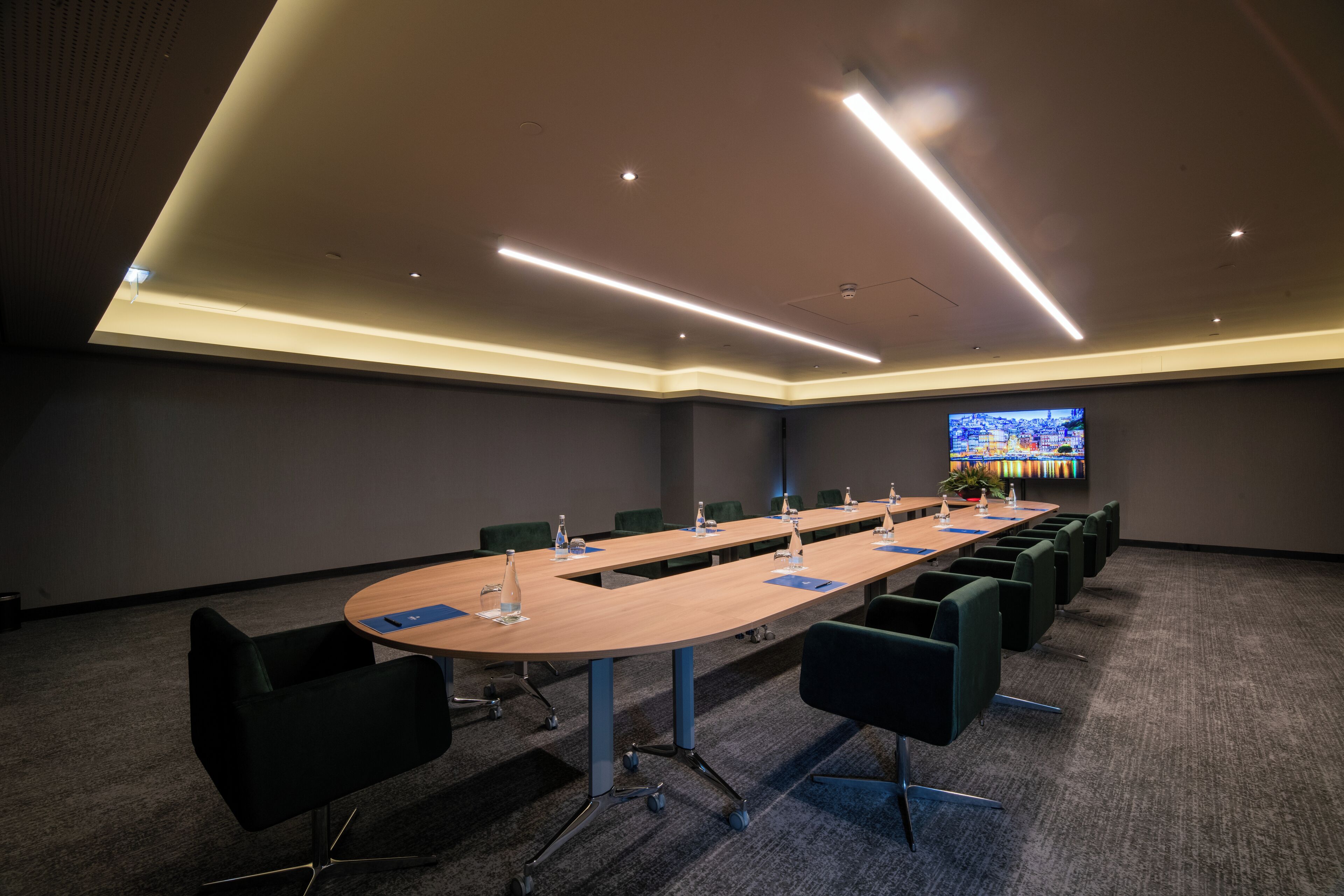 Une salle de conférence avec une longue table, des chaises et un grand écran.