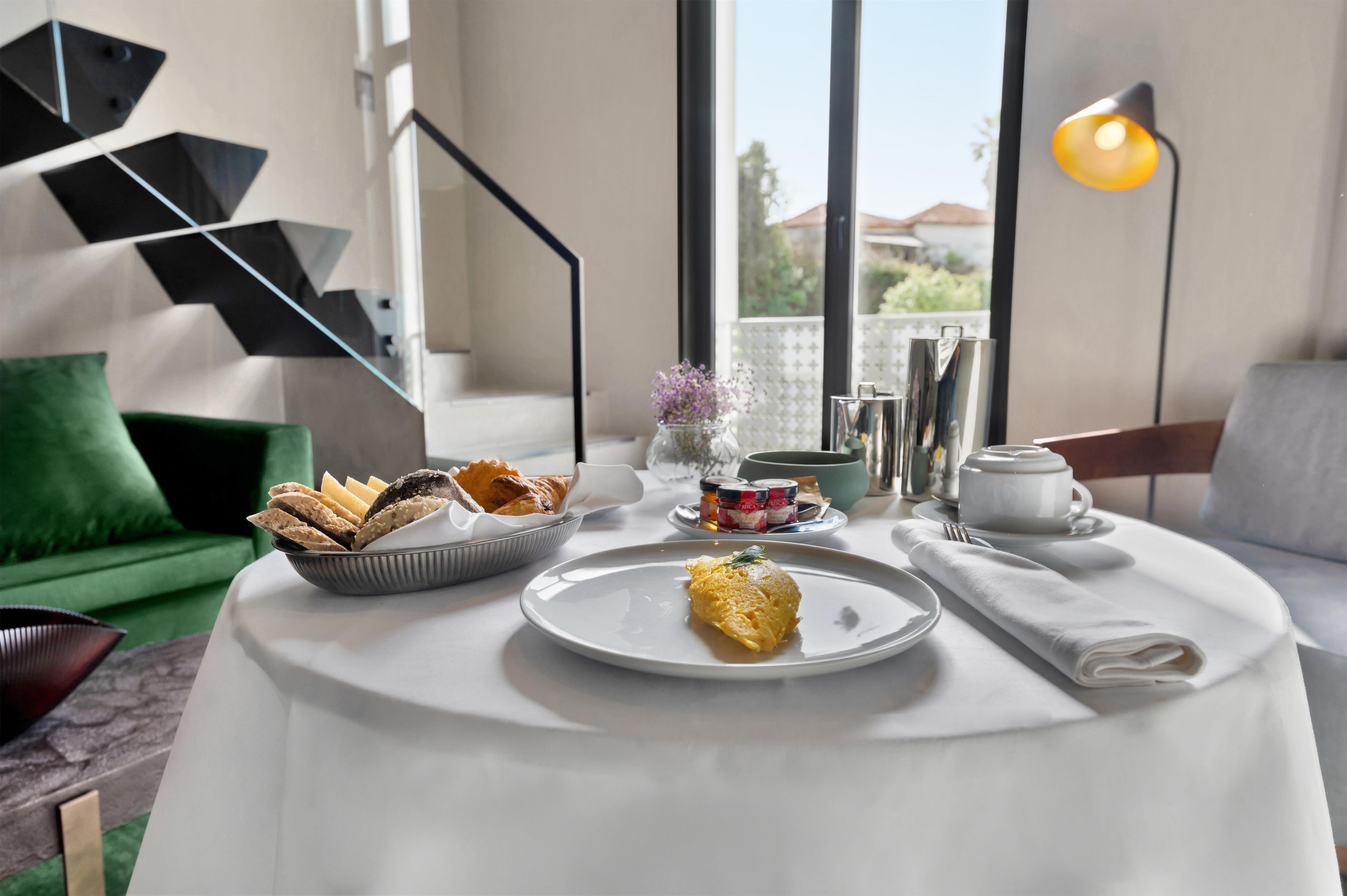 Een ontbijttafel met een bord eieren, een schaal gebak en bijgerechten.