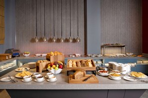 A buffet setup with various food items, including waffles, pastries, and fruits. - Hampton by Hilton Tashkent (Tashkent)