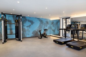 A gym with treadmills, a stationary bike, and weightlifting equipment. - Hampton by Hilton Tashkent (Tashkent)