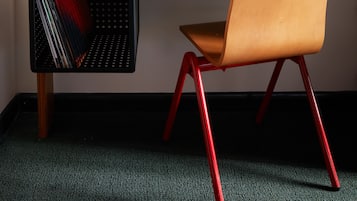 Un escritorio de madera con un tocadiscos, una silla roja y una lámpara de escritorio.