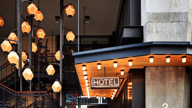 A hotel entrance with a sign reading "HOTEL 252", a staircase, and hexagonal pendant lights. - Ace Hotel Brooklyn (Brooklyn)