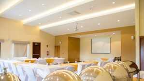 A conference room with tables, chairs, and a projector screen. - Los Brezos Boutique Hotel (Volcan)