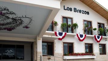Hotel Los Brezos met een moderne gevel, meerdere balkons met plantenbakken en een duidelijke entree.