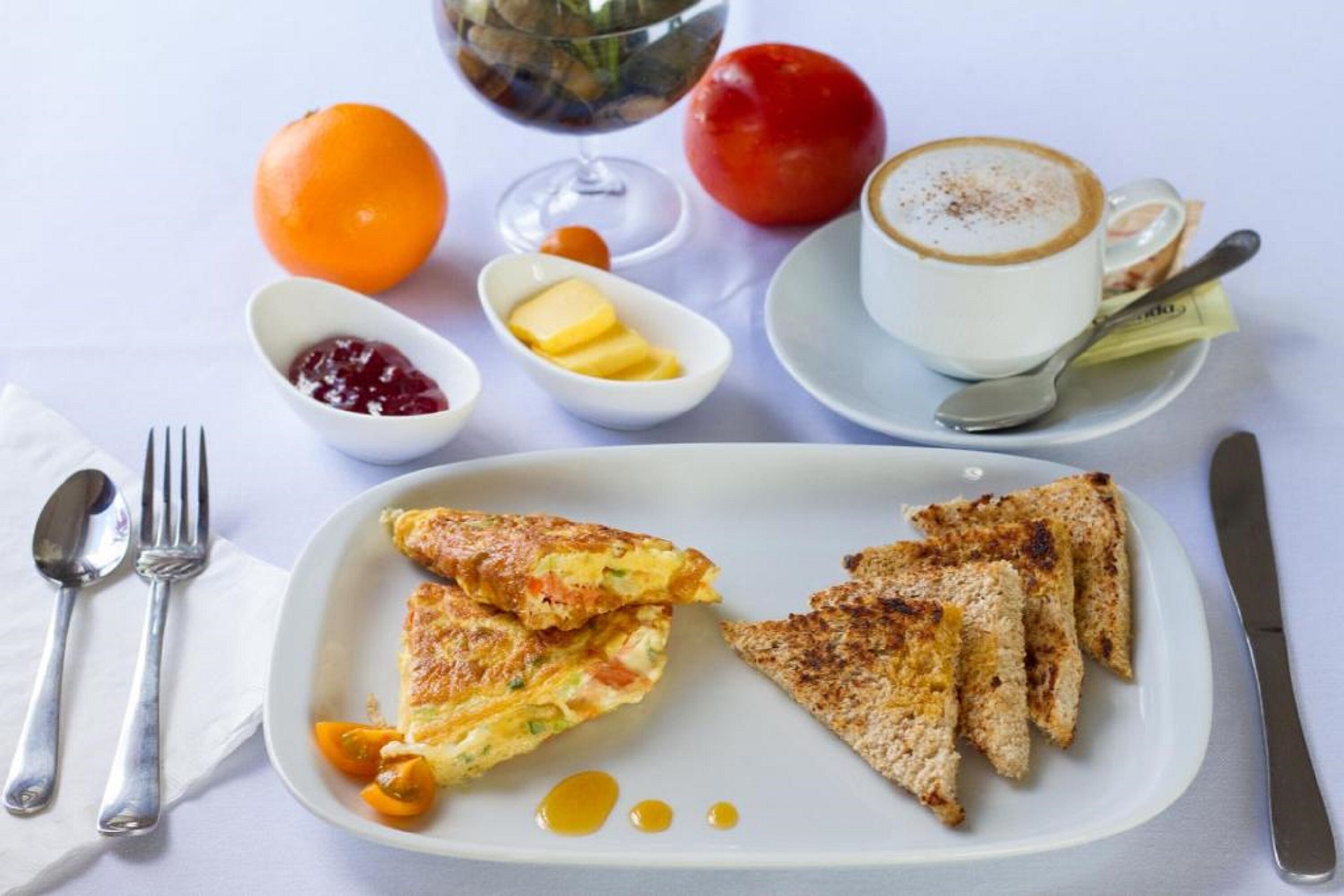 A breakfast plate with toast, a glass of coffee, and a fruit bowl.