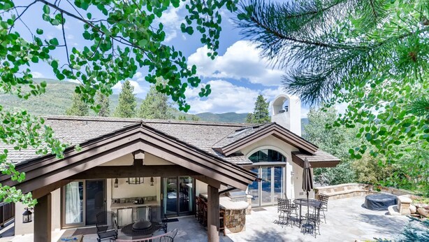 A house with a covered patio, outdoor seating, and a stone fireplace. - 2-2122 Vermont Road (Vail)