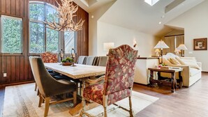 A dining area with a wooden table, floral upholstered chairs, and a chandelier. - 2-2122 Vermont Road (Vail)