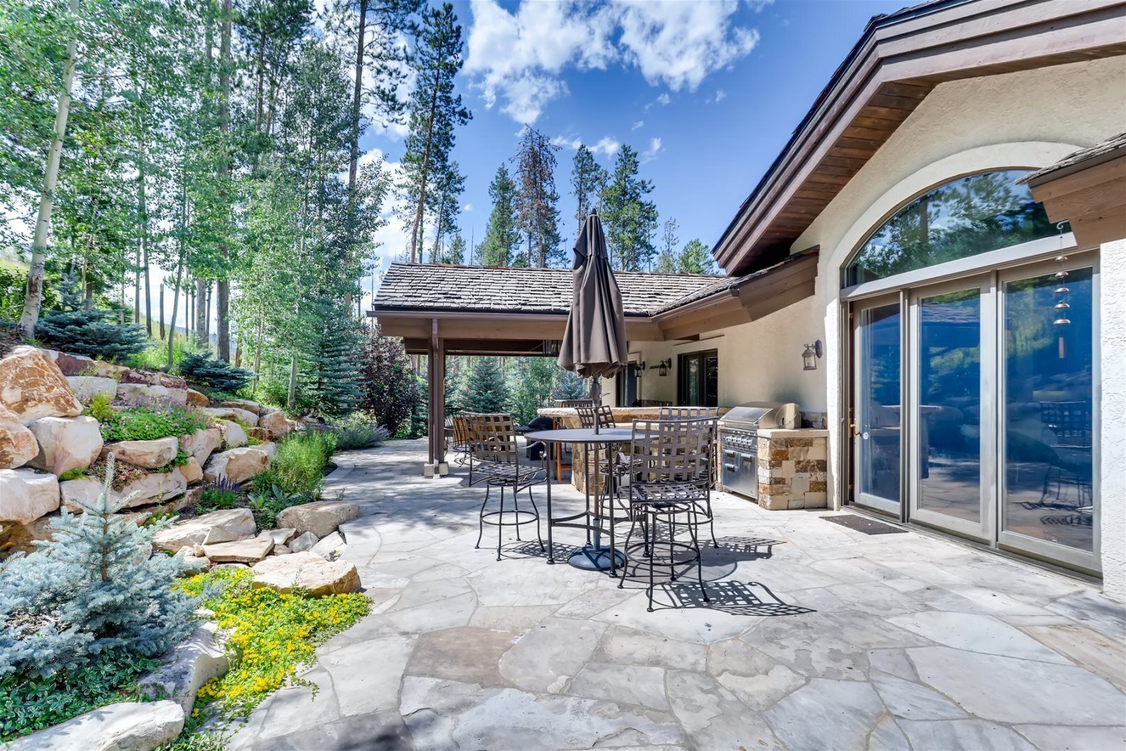 A patio with stone flooring, outdoor furniture, and a grill area.