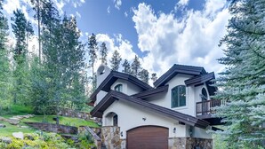 A modern two-story house with a stone facade, a wooden garage door, and a balcony. - 2-2122 Vermont Road (Vail)
