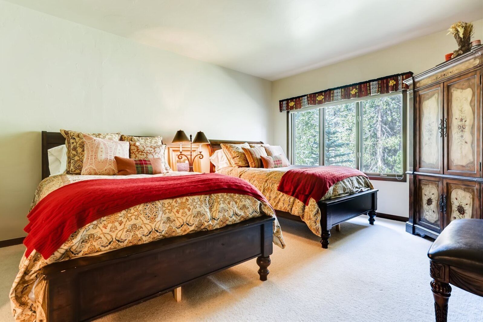 Une chambre avec deux lits, une grande fenêtre et une commode ancienne.