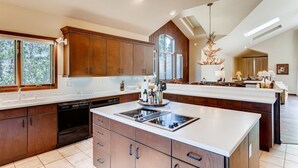 A spacious kitchen with wooden cabinets, a central island, and a large window providing natural light. - 2-2122 Vermont Road (Vail)
