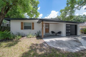 Ein Bungalow mit Veranda, Garage und kleiner Terrasse.