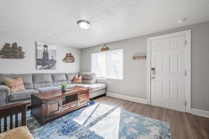Relax in this stylish living room with a grey sofa, wooden coffee table, and artwork-adorned walls.