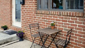 Et murstenshus med et skilt med nummer 618, et vindue og en lille terrasse med et bord og stole.