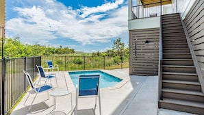 A swimming pool with lounge chairs and a staircase leading to an upper level. - 1505 Sandpiper Ln | Private pool, beach/lagoon access! (Gulf Shores)