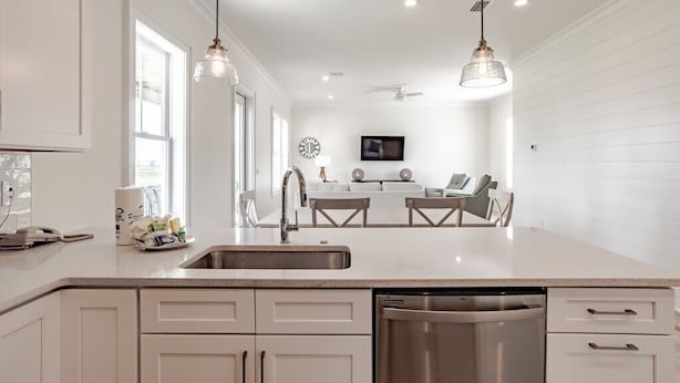 A modern kitchen with white cabinetry, a stainless steel dishwasher, and pendant lighting. - 1505 Sandpiper Ln | Private pool, beach/lagoon access! (Gulf Shores)