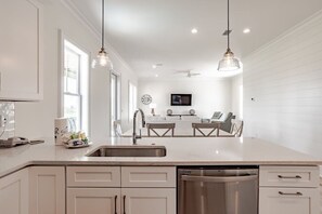 A modern kitchen with white cabinetry, a stainless steel dishwasher, and pendant lighting. - 1505 Sandpiper Ln | Private pool, beach/lagoon access! (Gulf Shores)