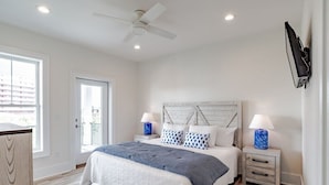 A bedroom with a bed, nightstands, a ceiling fan, and a TV mounted on the wall. - 1505 Sandpiper Ln | Private pool, beach/lagoon access! (Gulf Shores)