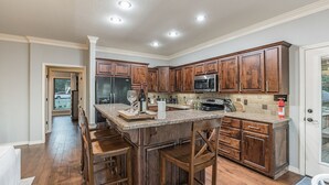 A kitchen with wooden cabinets, a granite countertop, and a stainless steel refrigerator. - ON Mt Nebo State Park Luxury Mountain Retreat with Above the-clouds sunrise view (Dardanelle)