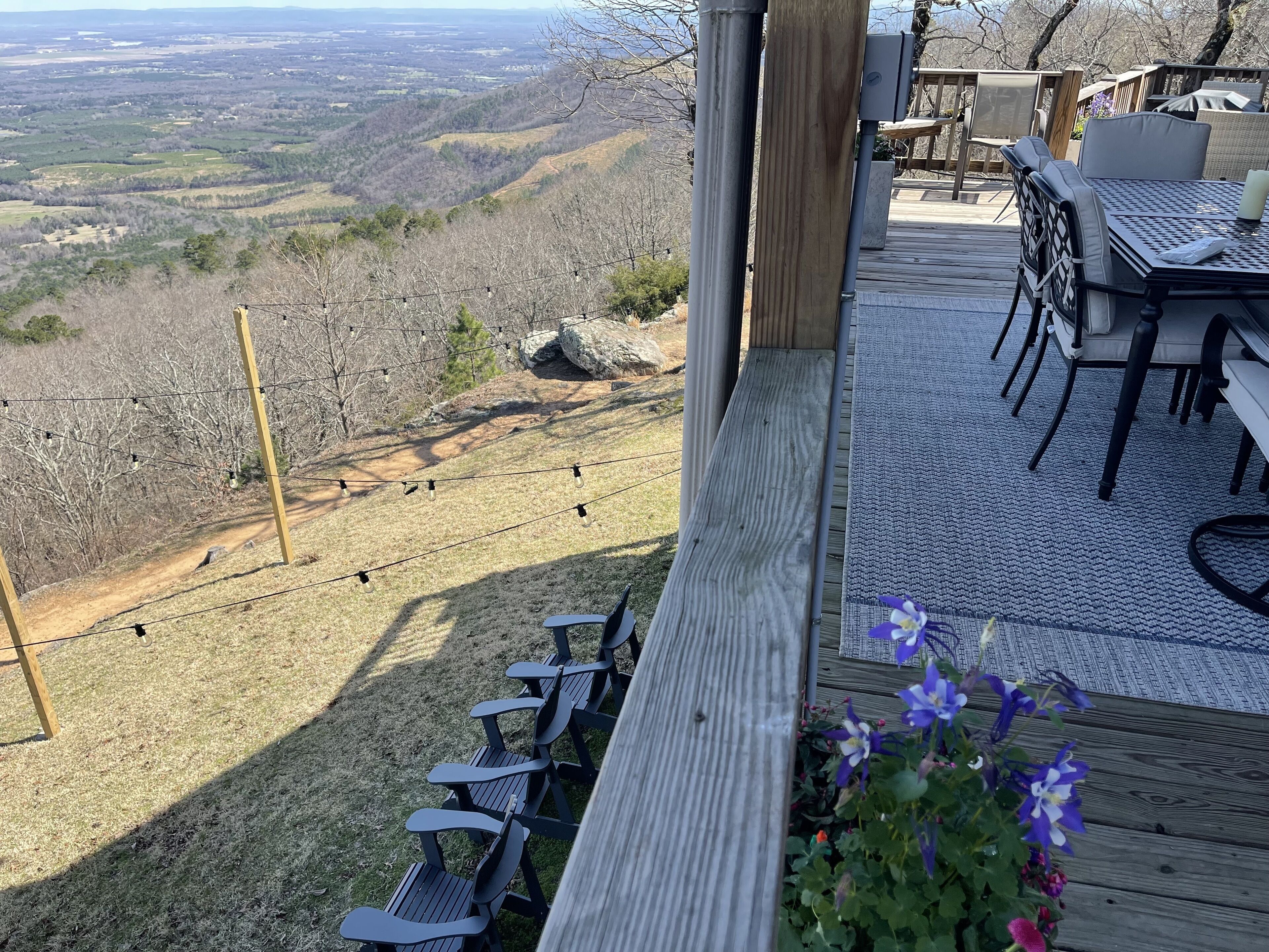 A deck with outdoor seating, overlooking a hilly landscape.