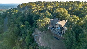 A large house surrounded by dense forest, with a visible deck and outdoor seating area. - ON Mt Nebo State Park Luxury Mountain Retreat with Above the-clouds sunrise view (Dardanelle)
