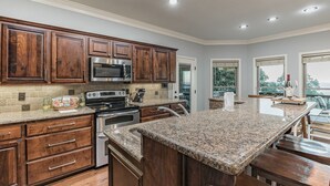 A modern kitchen with granite countertops, stainless steel appliances, and wooden cabinetry. - ON Mt Nebo State Park Luxury Mountain Retreat with Above the-clouds sunrise view (Dardanelle)