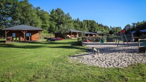 Un camping con cabañas de madera, un parque infantil y una zona de arena.