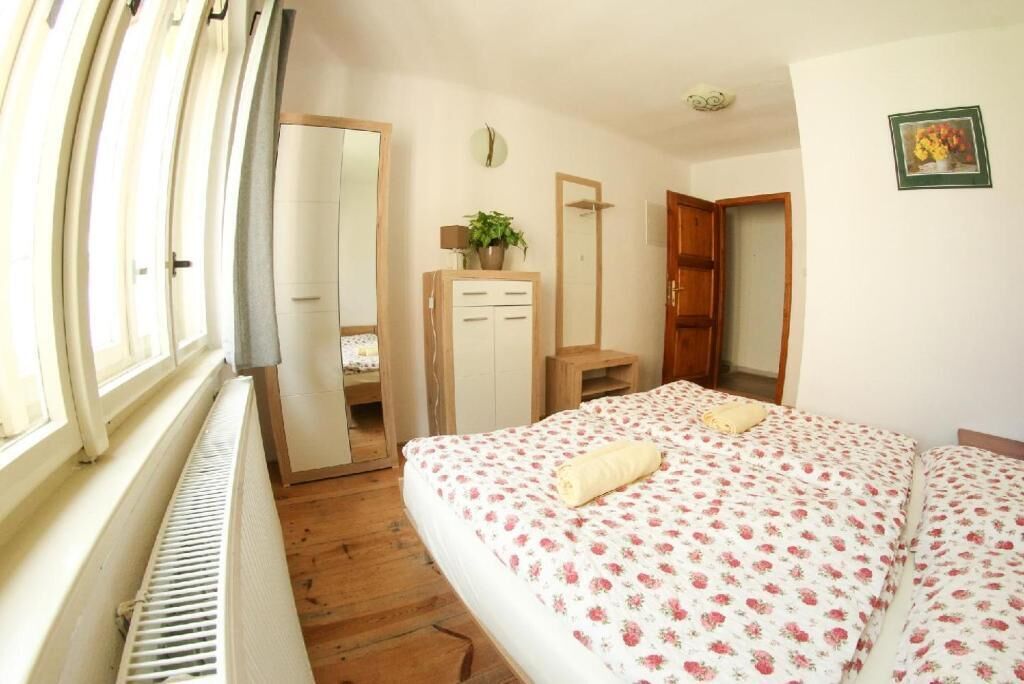 Une chambre à coucher comprenant un lit, une commode, un miroir, un radiateur et une fenêtre.