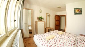 A bedroom with a bed, a dresser, a mirror, a radiator, and a window. - Beautiful 4 Bedroom apartment (Chvalsiny)