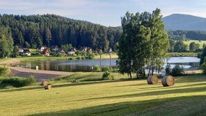 A rural landscape with houses, a lake, and hay bales. - Beautiful 4 Bedroom apartment (Chvalsiny)