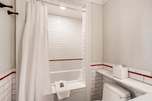 Un baño pequeño y blanco con ducha, inodoro y lavamanos.