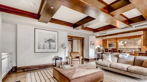 A spacious living room with a large sofa, a coffee table, and a striped rug. There is a framed picture on the wall and a chair in the corner. - 1a-owb 36 (Vail)