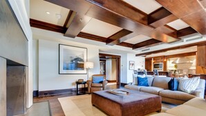 A spacious living room with a fireplace, a large sofa set, and a kitchen area visible through an open doorway. - 1a-owb 36 (Vail)