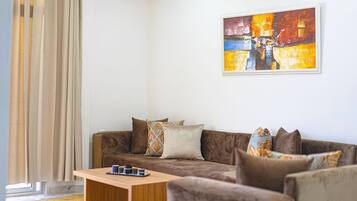 A living room with a brown sofa, a coffee table, and a painting on the wall.