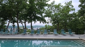 A poolside area with lounge chairs and a view of a lake.