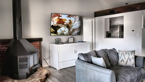 A living room with a fireplace, a sofa, and a television mounted on the wall.