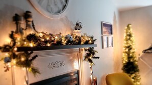 A cozy living room with a fireplace, a yellow armchair, a Christmas tree, and festive decorations.