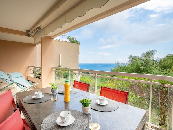 A balcony with a table set for two, overlooking a scenic view of the sea.