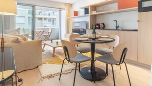 Un appartement moderne comprenant un coin repas, une cuisine et un balcon avec vue sur les immeubles.