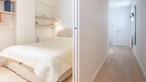 Une chambre à coucher au style minimaliste, avec un lit, des tables de chevet et un couloir menant à une porte.