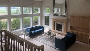 A spacious living room with a blue sofa, a fireplace, and large windows offering a view of greenery. - The perfect place for a vacation or reunion.  (Saint Anthony)