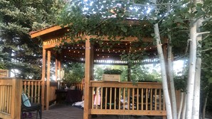 A wooden deck with a pergola, string lights, and a table with chairs. - The perfect place for a vacation or reunion.  (Saint Anthony)